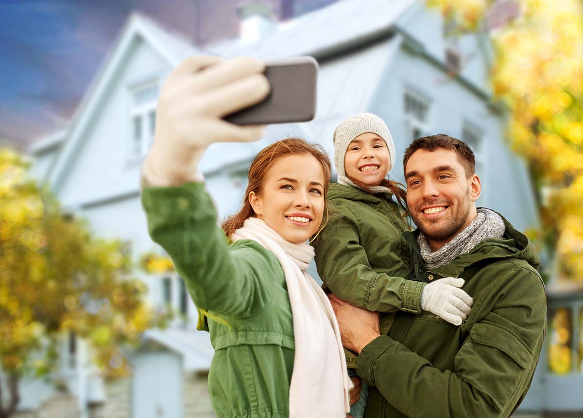Family taking a selfie in front of their new house after receiving home inspection services 
